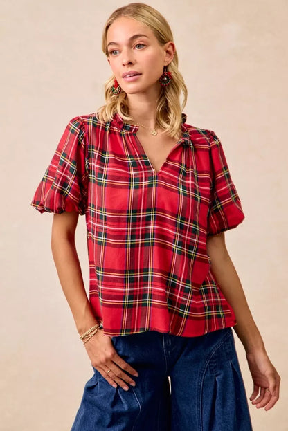 Red and green plaid holiday blouse with short ruffled sleeves, a soft flowy silhouette, and a narrow V-neck opening.