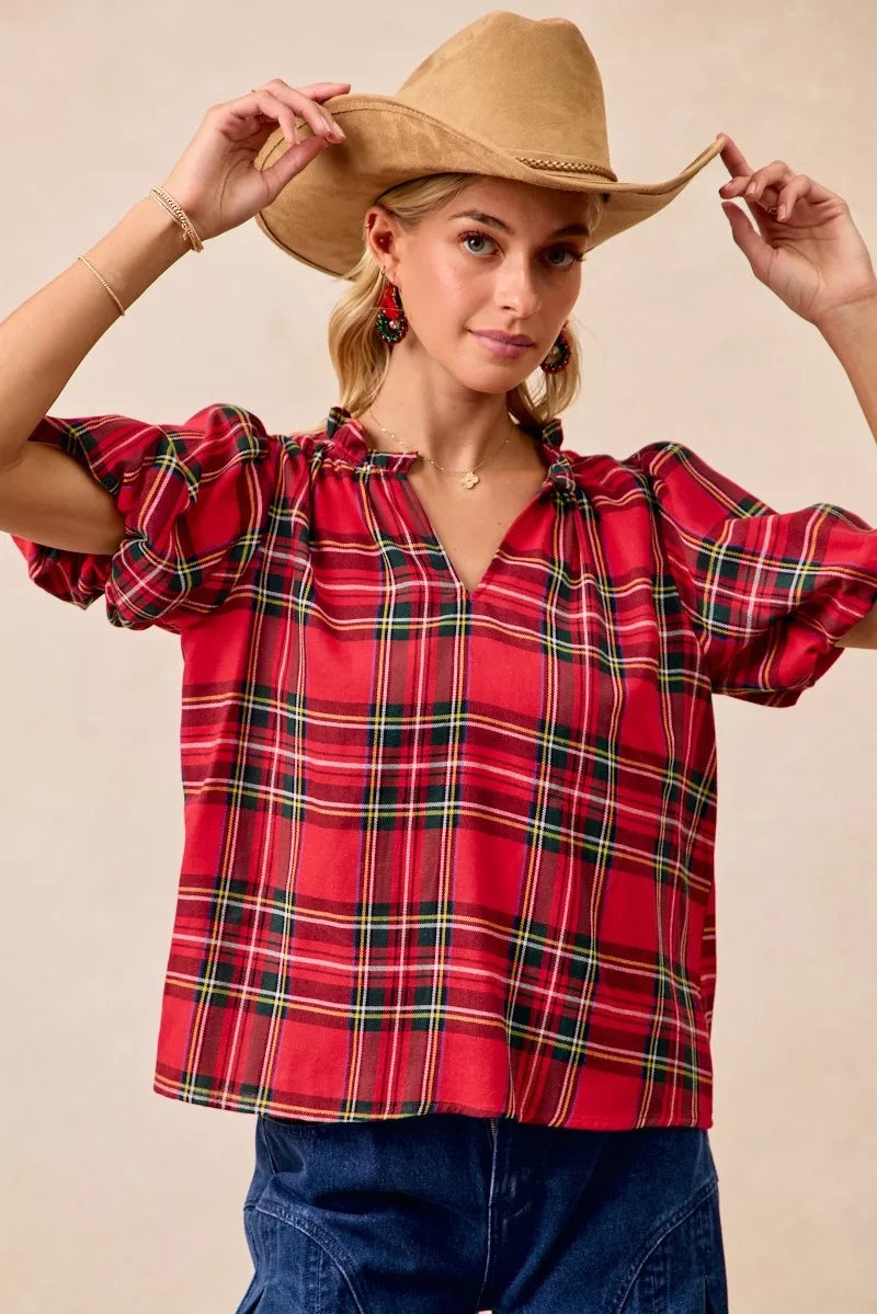 Red and green plaid holiday blouse with short ruffled sleeves, a soft flowy silhouette, and a narrow V-neck opening.
