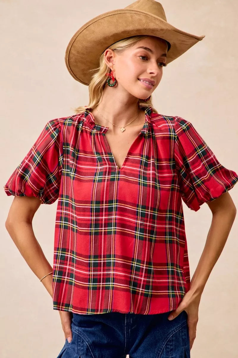 Red and green plaid holiday blouse with short ruffled sleeves, a soft flowy silhouette, and a narrow V-neck opening.